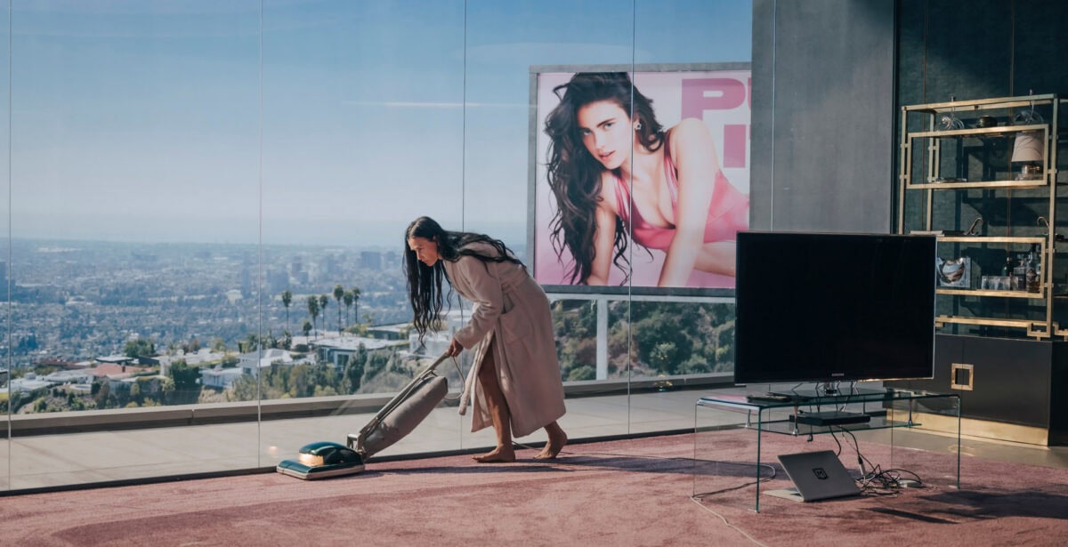 Demi Moore passe l'aspirateur dans son appartement devant une image de Margaret Qualley dans The Substance